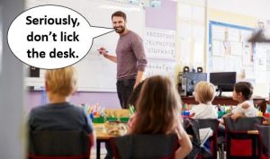Male teacher talking to primary students with speech bubble saying "Seriously, don’t lick the desk."